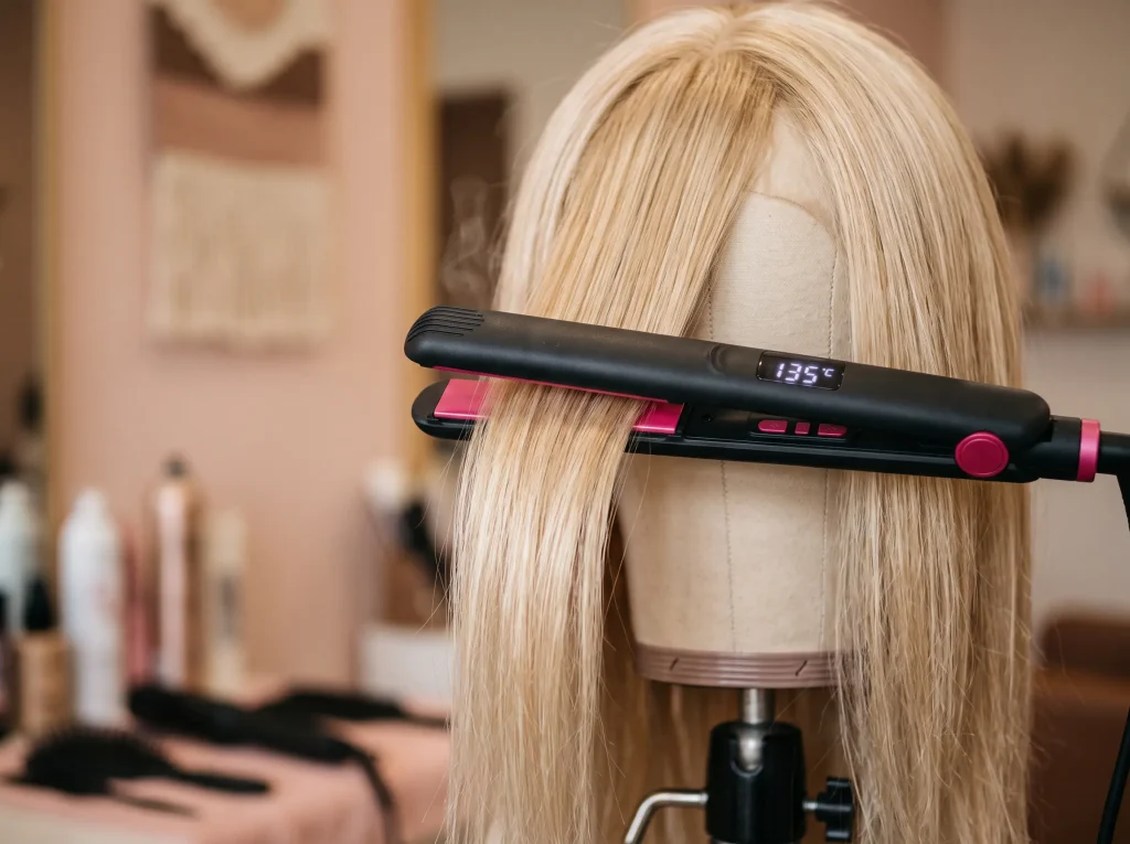 heat-resistant-wig-styling-temperature-test A flat iron on a low heat setting styling a single section of heat-resistant synthetic wig fiber